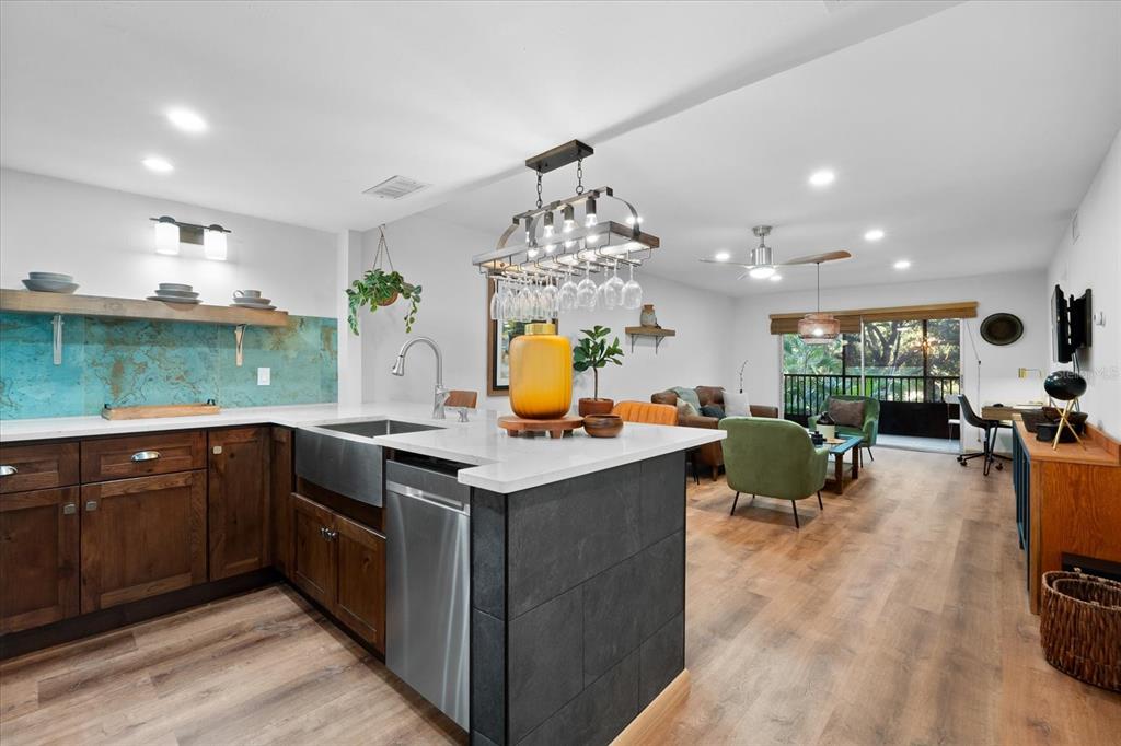 A kitchen with dark wood cabinets and a stone island opens into a living area — 3700 S OSPREY AVENUE UNIT 214, SARASOTA, FL