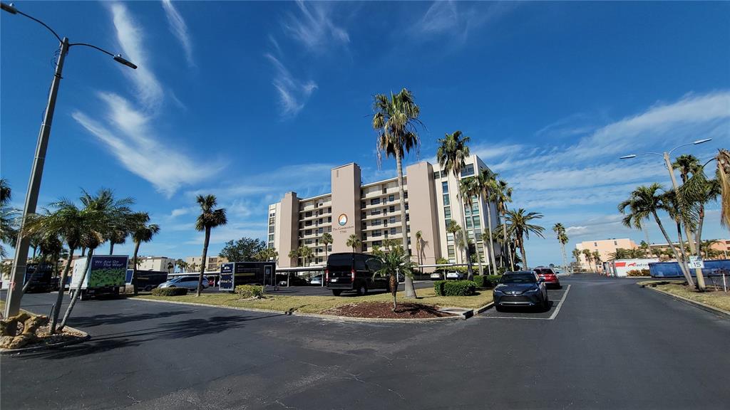 A multi-story apartment building stands in a parking lot surrounded by palm trees — 7700 SUN ISLAND DRIVE S UNIT 608, SOUTH PASADENA, FL