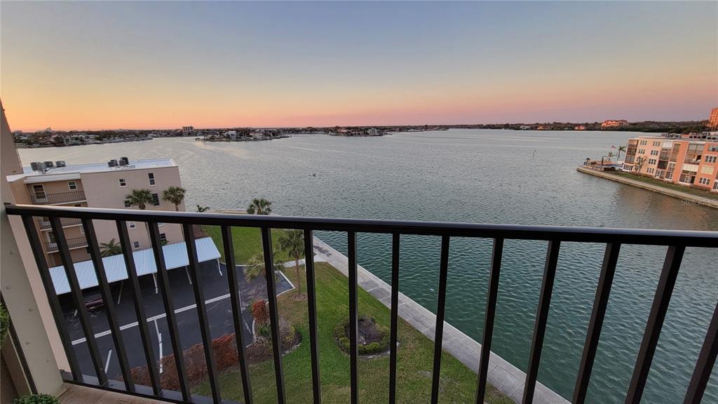 A balcony view overlooking a body of water, a parking lot, and nearby apartment buildings — 7700 SUN ISLAND DRIVE S UNIT 608, SOUTH PASADENA, FL