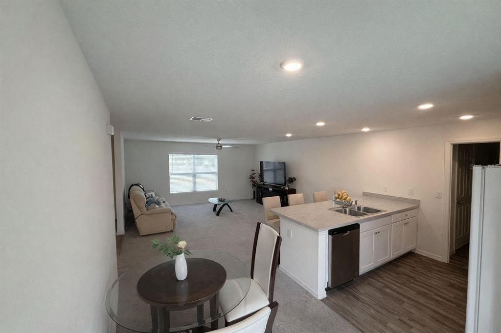 An open-concept living area features a kitchen island, dining table, and carpeted living room — 17103 SW 22ND TERRACE ROAD, OCALA, FL