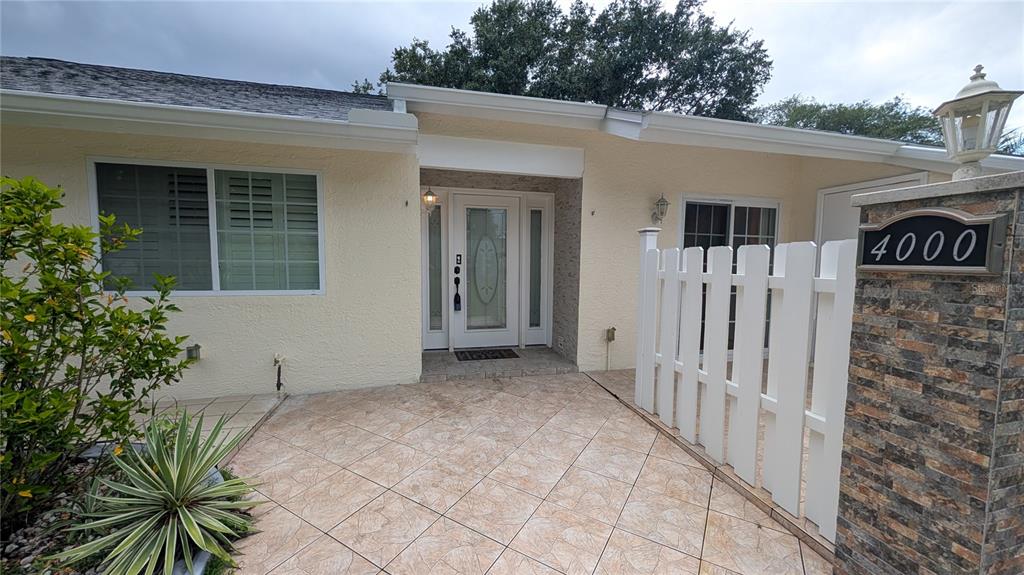 The exterior of a house features a tiled entryway, a white front door, and a fence — 4000 POINCIANA COURT, PALM HARBOR, FL