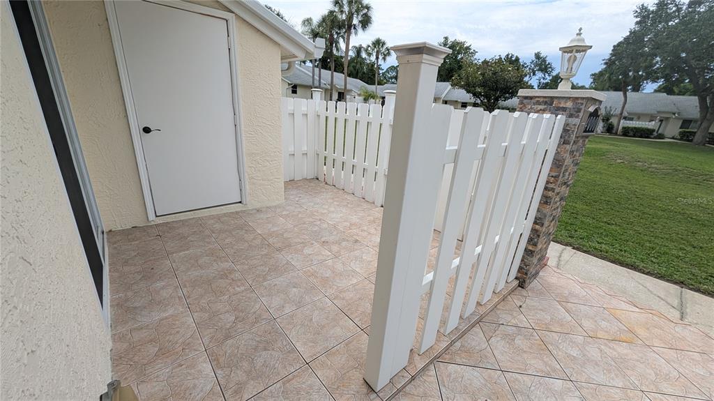A tiled outdoor patio features a white vinyl fence and a white entry door — 4000 POINCIANA COURT, PALM HARBOR, FL