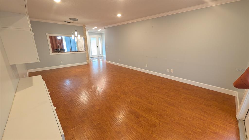 A living room features light blue walls, wood-look flooring, and a built-in white cabinet — 4000 POINCIANA COURT, PALM HARBOR, FL