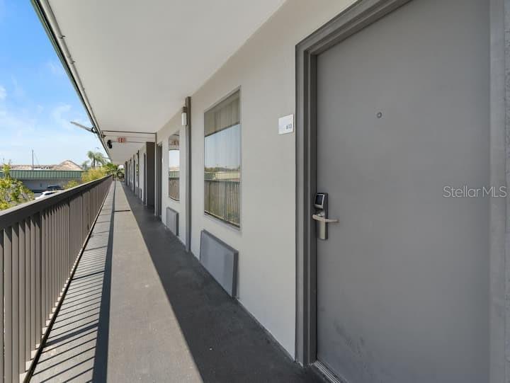 An exterior walkway with a metal railing leads past a gray door and windows — 7150 N TAMIAMI TRAIL UNIT S-613, SARASOTA, FL