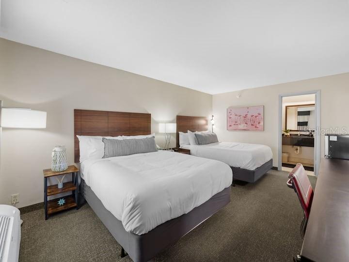 A hotel room features two queen beds, a wooden nightstand, and an attached bathroom — 7150 N TAMIAMI TRAIL UNIT S-613, SARASOTA, FL