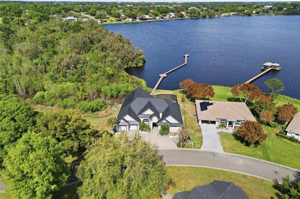 An aerial view shows a waterfront house with a pool, dock, and solar panels — 1028 S LAKE MARIAM DRIVE, WINTER HAVEN, FL