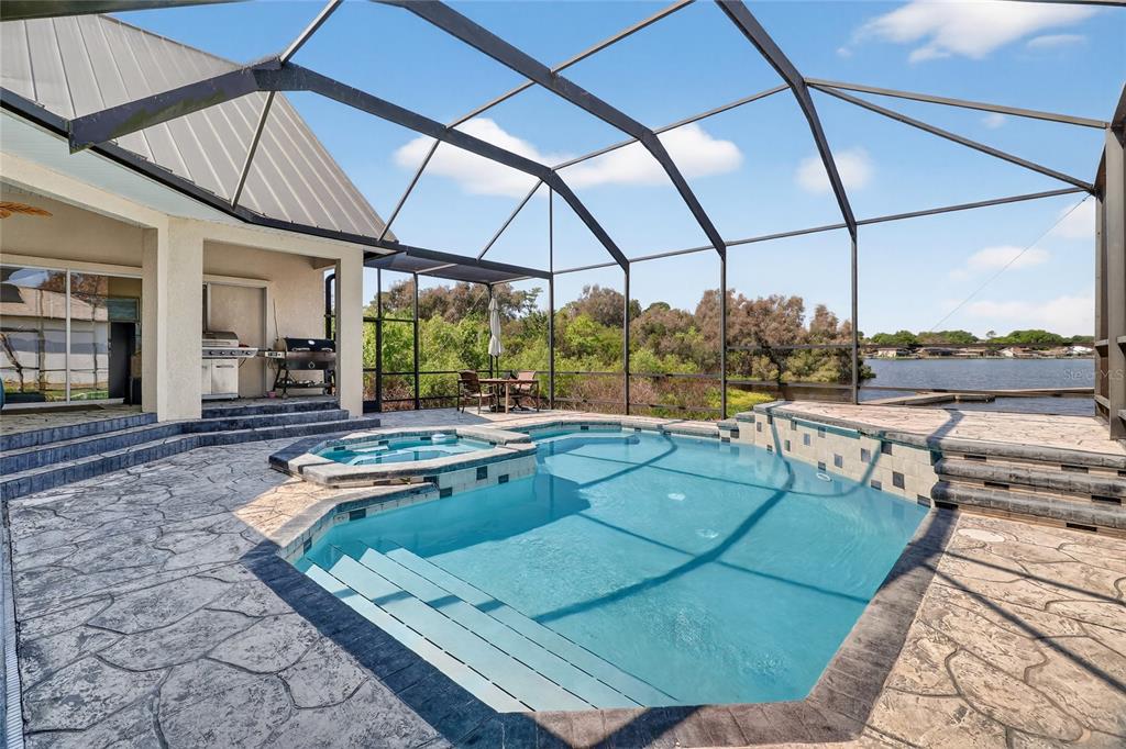 A screened-in pool and spa area with a patio overlooking a lake — 1028 S LAKE MARIAM DRIVE, WINTER HAVEN, FL