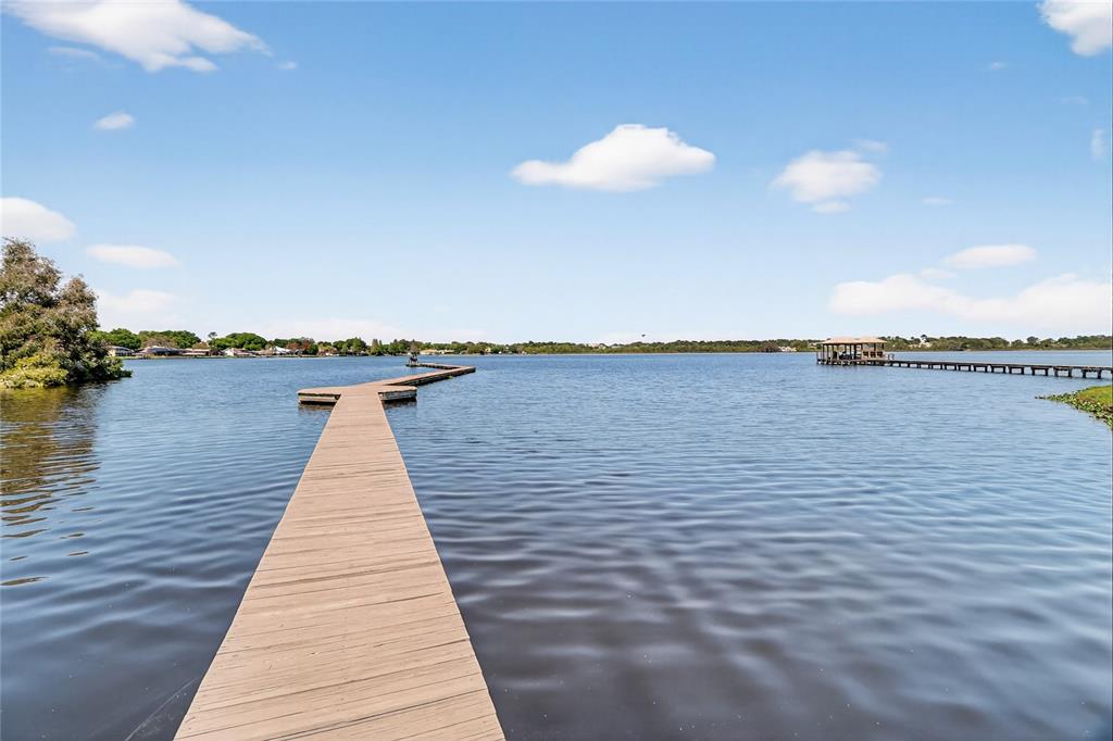 A long wooden pier extends into a calm lake under a bright blue sky — 1028 S LAKE MARIAM DRIVE, WINTER HAVEN, FL