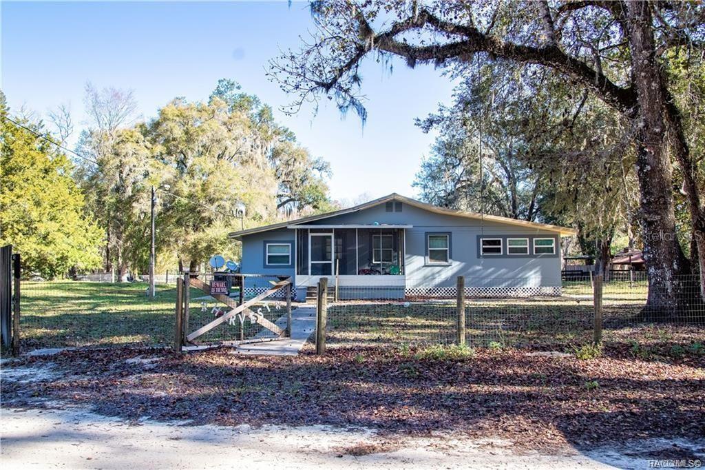 A single-story house with a screened front porch sits behind a fenced yard with trees — 7545 S OLD OAKS DRIVE, FLORAL CITY, FL