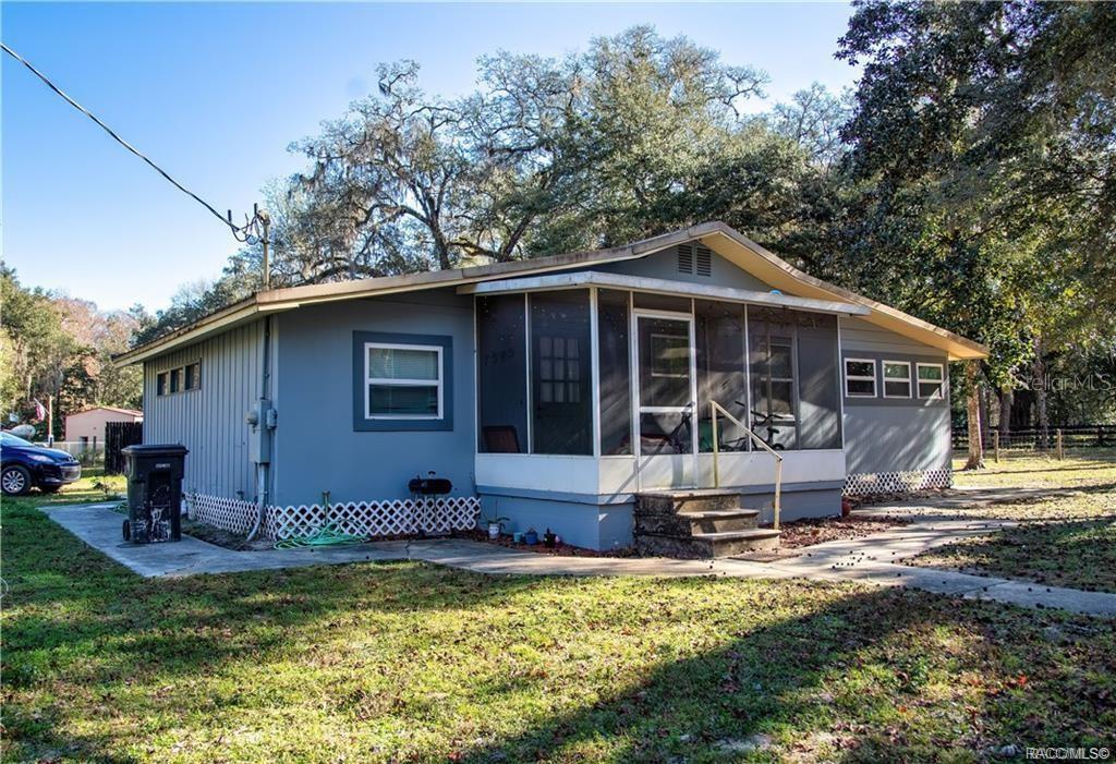 A single-story house with gray siding and a screened-in front porch sits on a lawn — 7545 S OLD OAKS DRIVE, FLORAL CITY, FL
