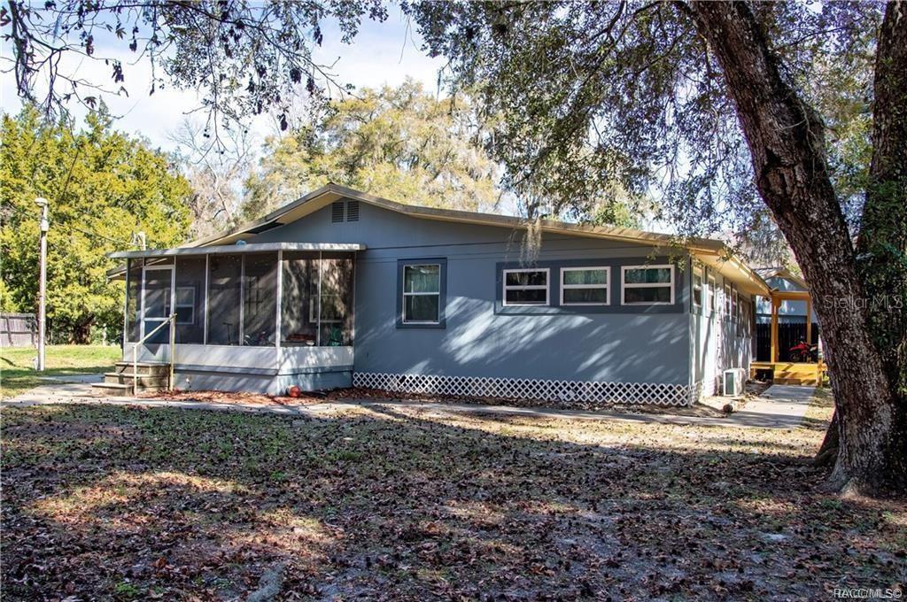 A gray single-story house with a screened-in porch and lattice skirting under large trees — 7545 S OLD OAKS DRIVE, FLORAL CITY, FL