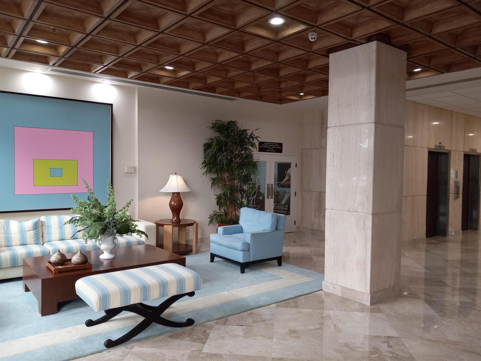A lobby features a coffered wood ceiling, marble floors, a blue area rug, and seating — 9960 S Ocean Drive # 502, Jensen Beach FL 34957, JENSEN BEACH, FL