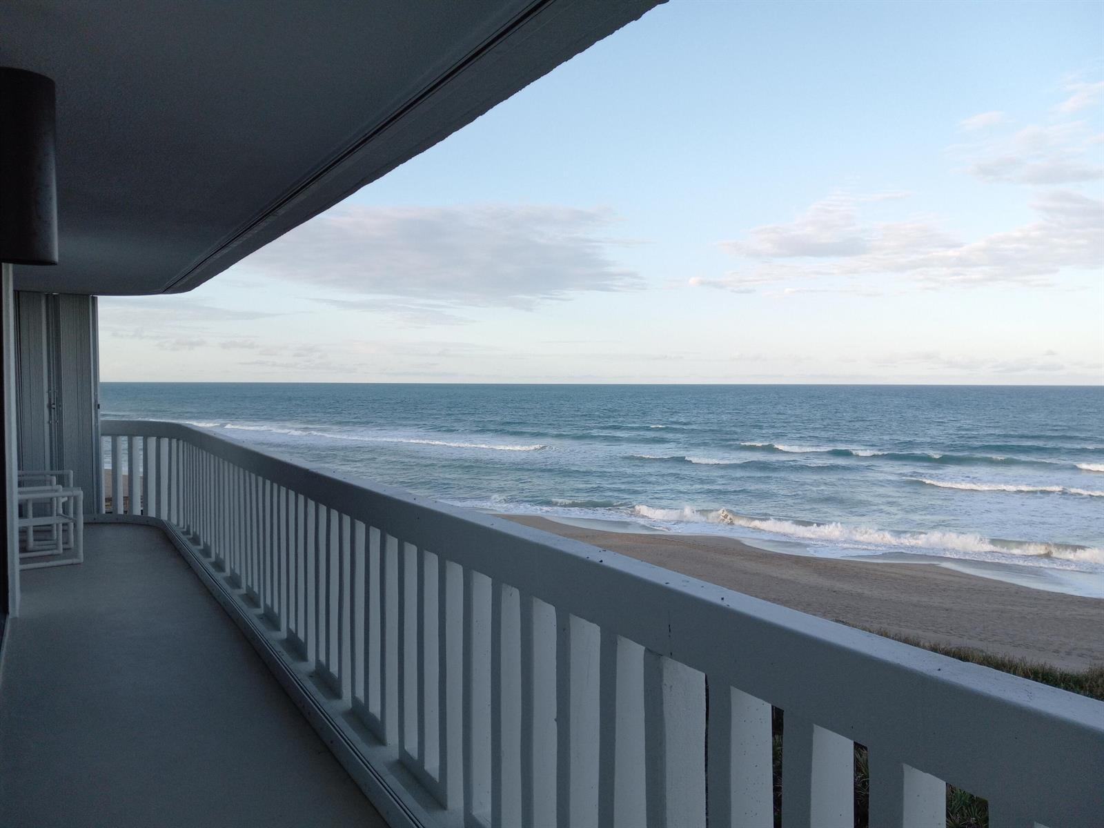 A balcony with a white railing overlooks a sandy beach and the ocean — 9960 S Ocean Drive # 502, Jensen Beach FL 34957, JENSEN BEACH, FL