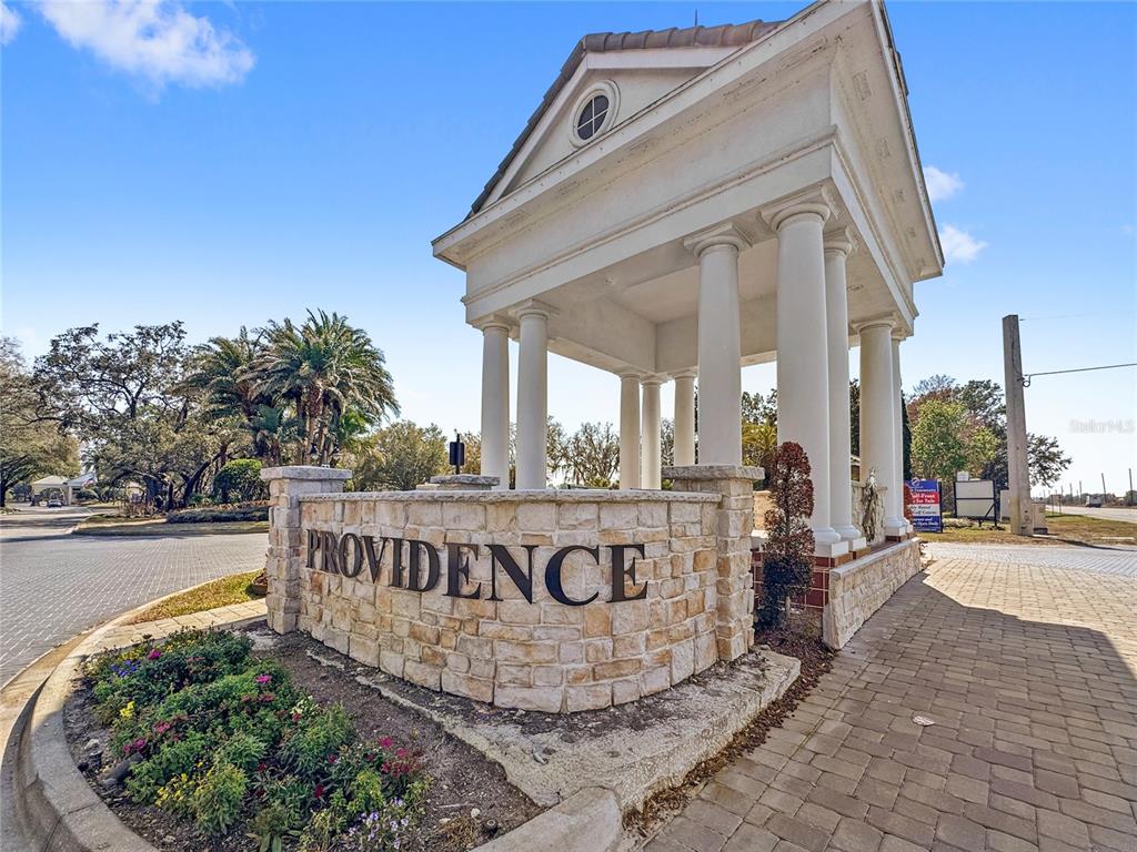 A stone monument with the word Providence stands before a white columned entrance structure — 3075 CAMDEN WAY, DAVENPORT, FL