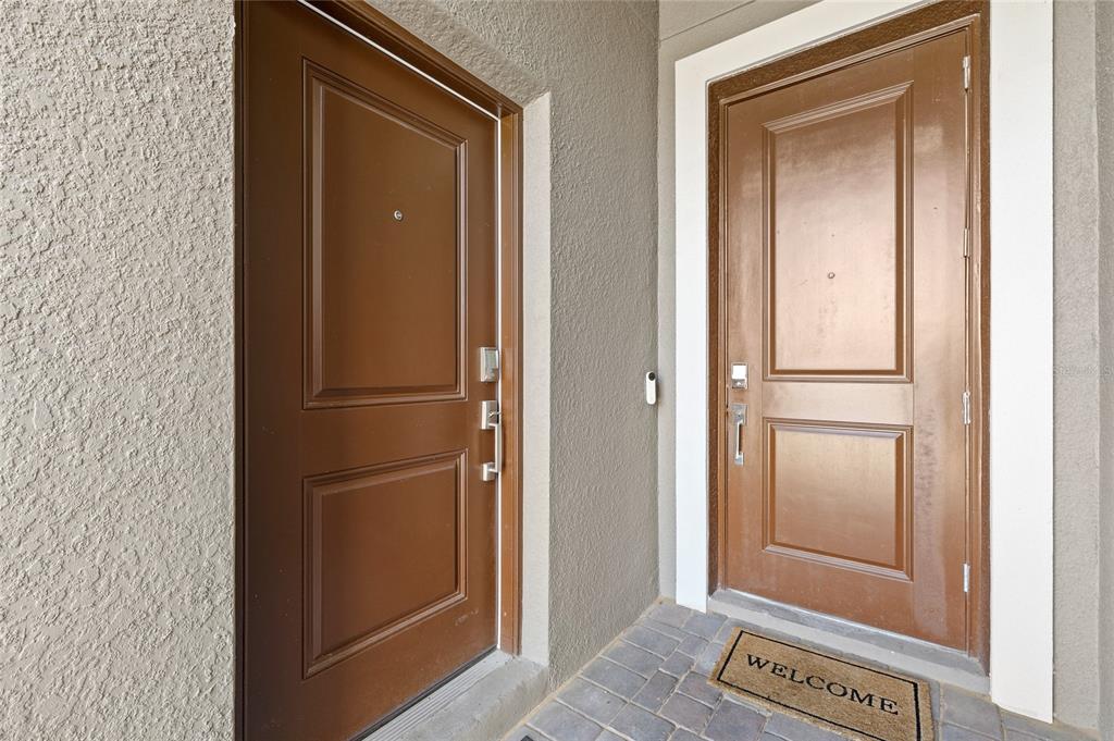 Two brown doors with panels and hardware are set into a textured gray exterior wall — 3075 CAMDEN WAY, DAVENPORT, FL