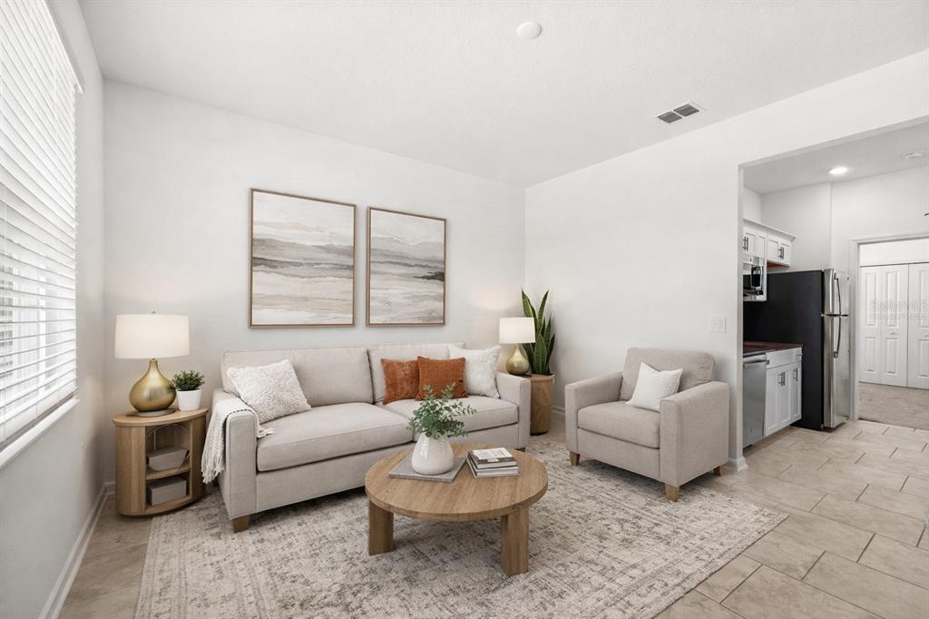 A living room features a beige sofa, matching armchair, round coffee table, and tile flooring — 3075 CAMDEN WAY, DAVENPORT, FL