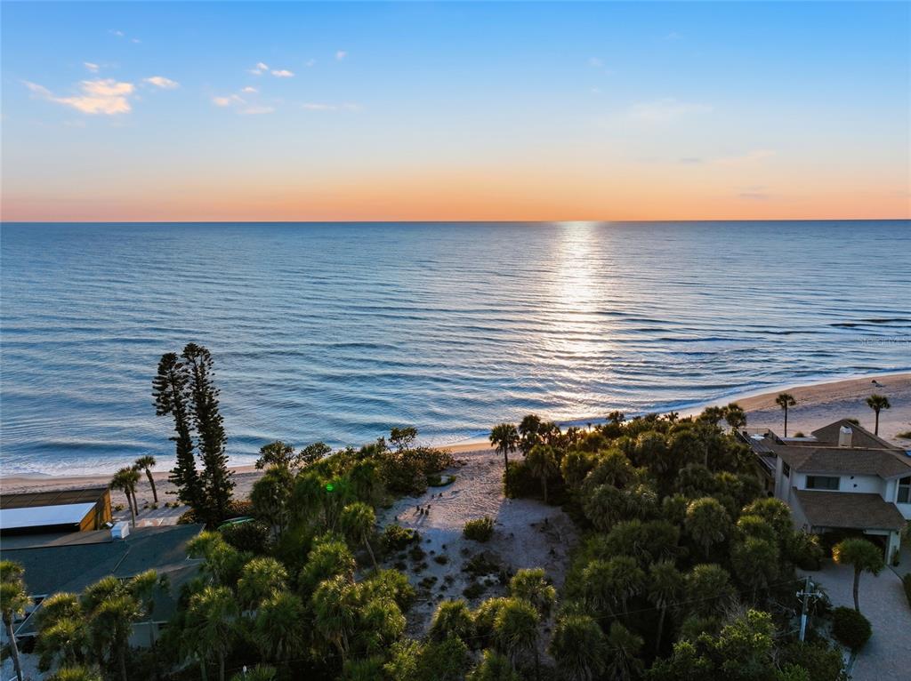 An aerial view of a sandy beach, ocean, and coastal vegetation with nearby residential homes — 765 N MANASOTA KEY ROAD, ENGLEWOOD, FL