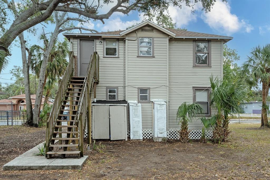 The exterior of a two-story house features light-colored siding, a wooden staircase, and storage units — 1701 14TH UNIT B, ST PETERSBURG, FL