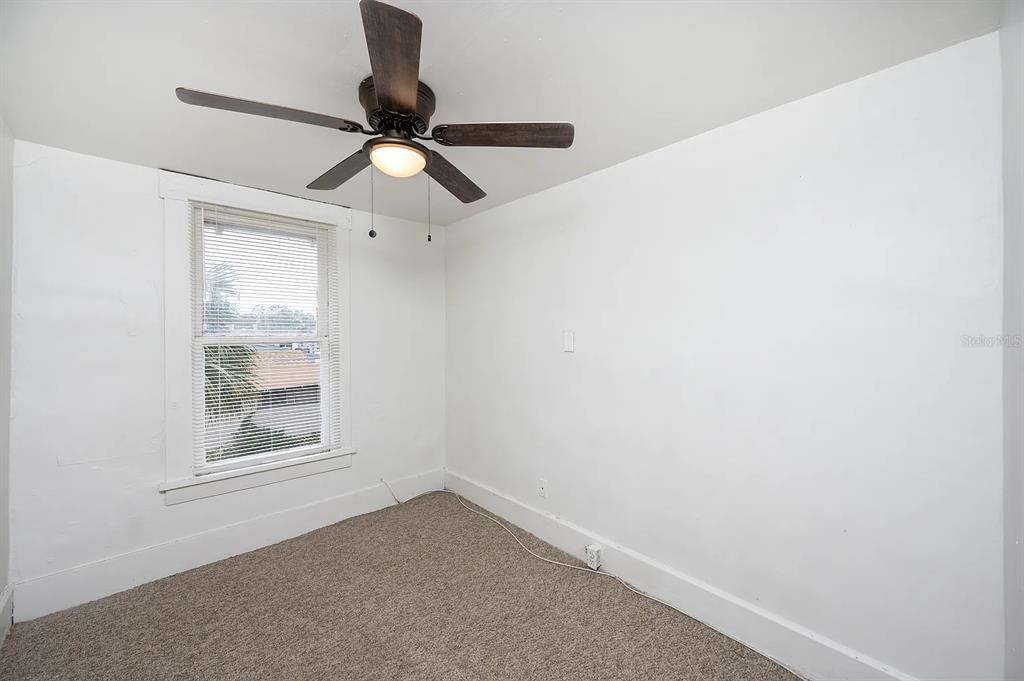 A small, empty bedroom with white walls, beige carpet, and a ceiling fan — 1701 14TH UNIT B, ST PETERSBURG, FL