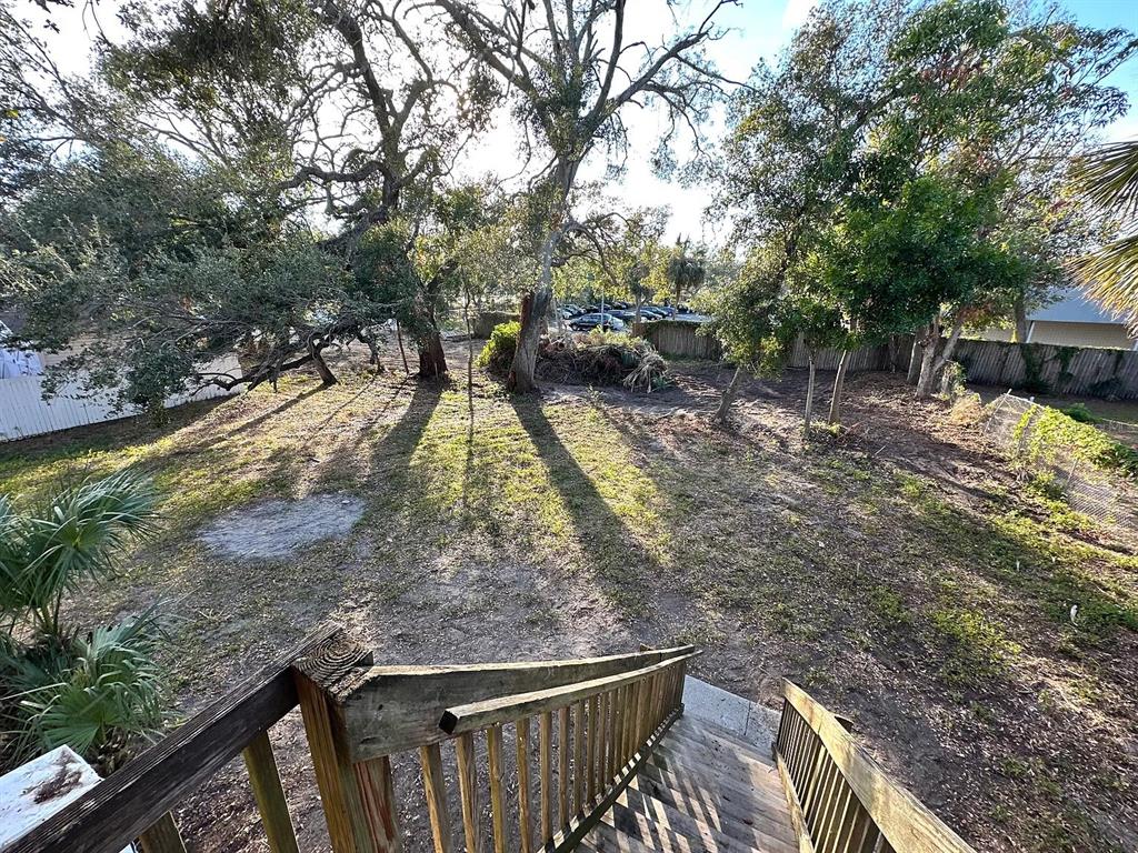 A wooden staircase leads down to a large, tree-shaded backyard with a dirt ground — 1701 14TH UNIT B, ST PETERSBURG, FL