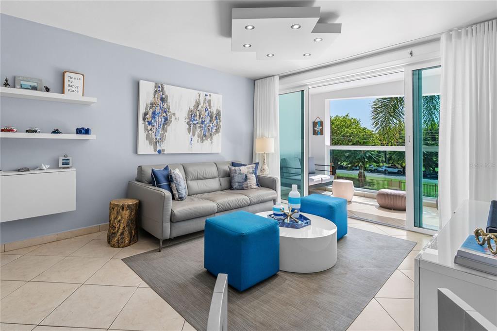 A living room features a grey sofa, blue ottomans, a white coffee table, and balcony access — 115 ESQ CAMBIJA STREET UNIT 2B, RINCON, PR