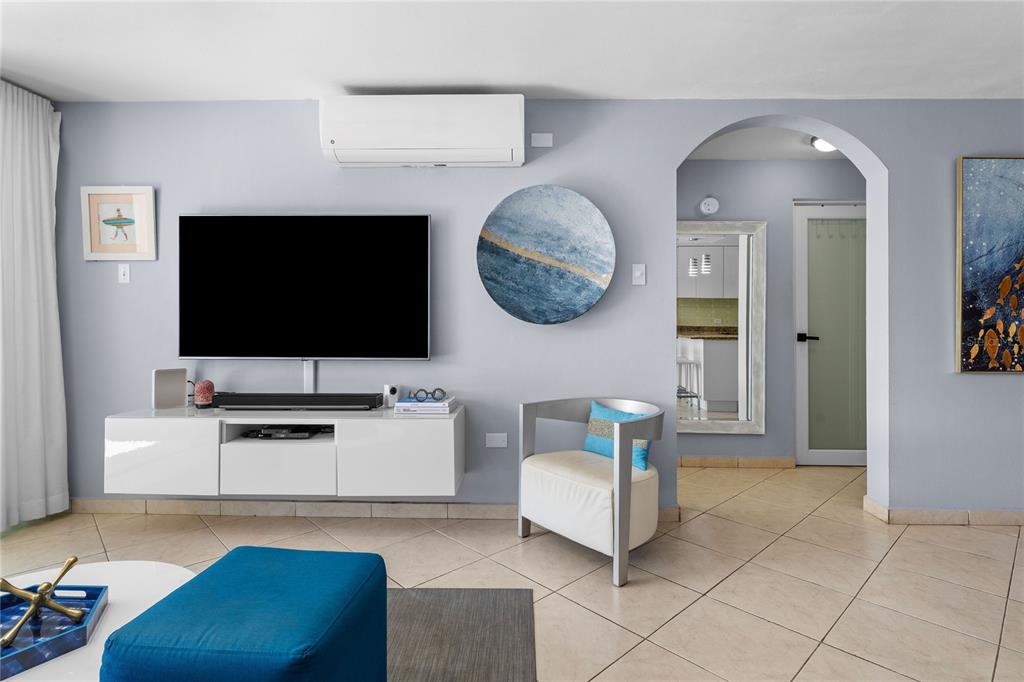 A living room features a wall-mounted television, a white console, and a modern accent chair — 115 ESQ CAMBIJA STREET UNIT 2B, RINCON, PR