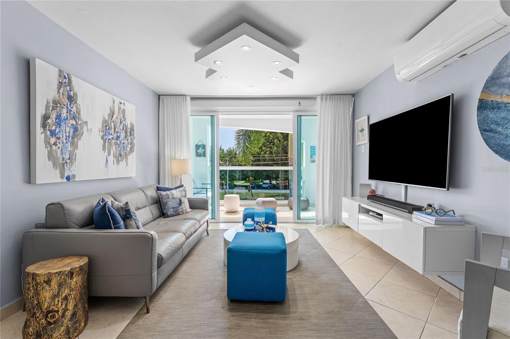 A living room features a gray sofa, blue ottomans, a white media console, and balcony access — 115 ESQ CAMBIJA STREET UNIT 2B, RINCON, PR