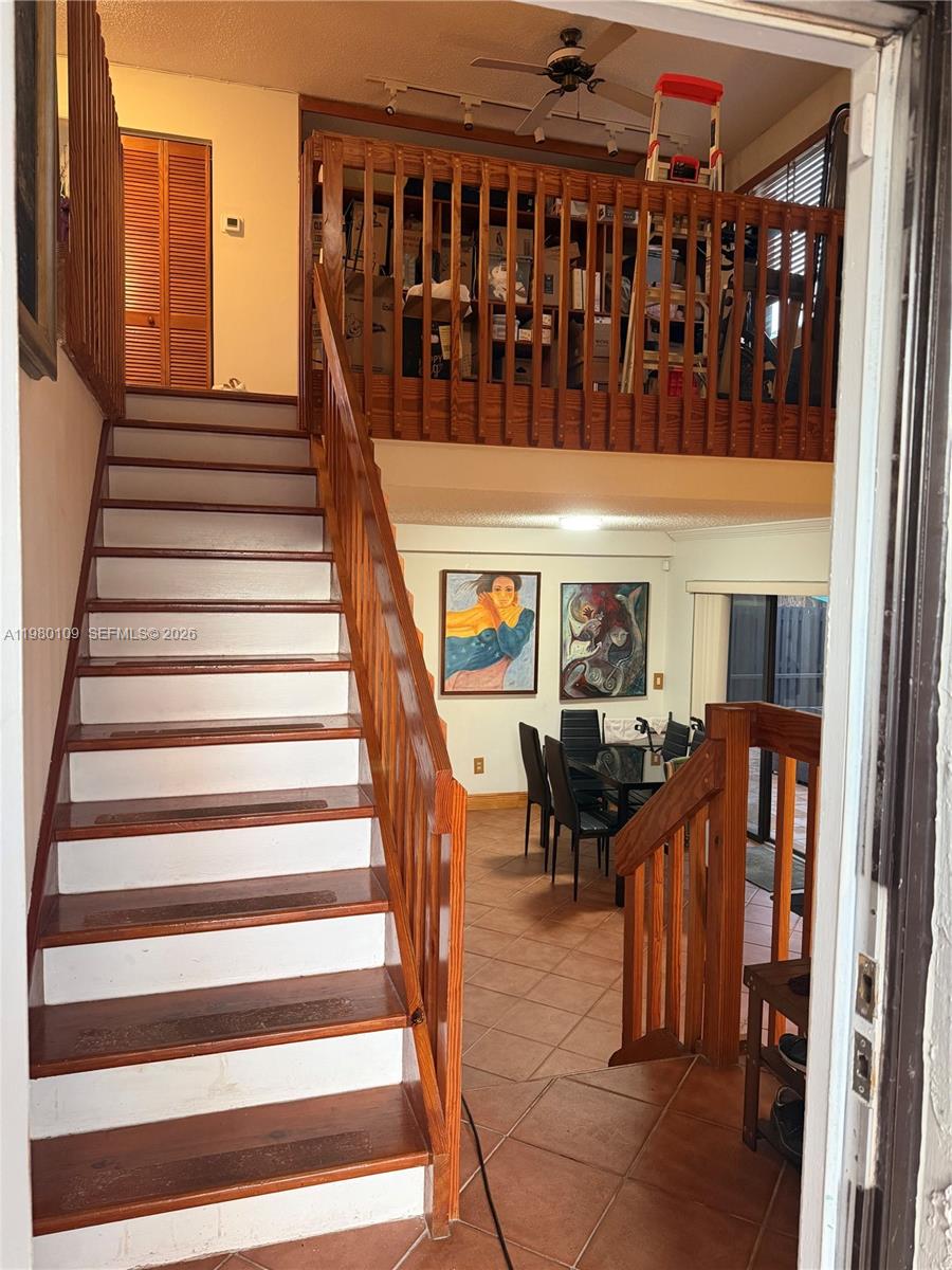 A staircase with wooden treads leads to a loft overlooking a dining area with tile floors — 15202 SW 46th Ln # 75, Miami FL 33185, MIAMI, FL
