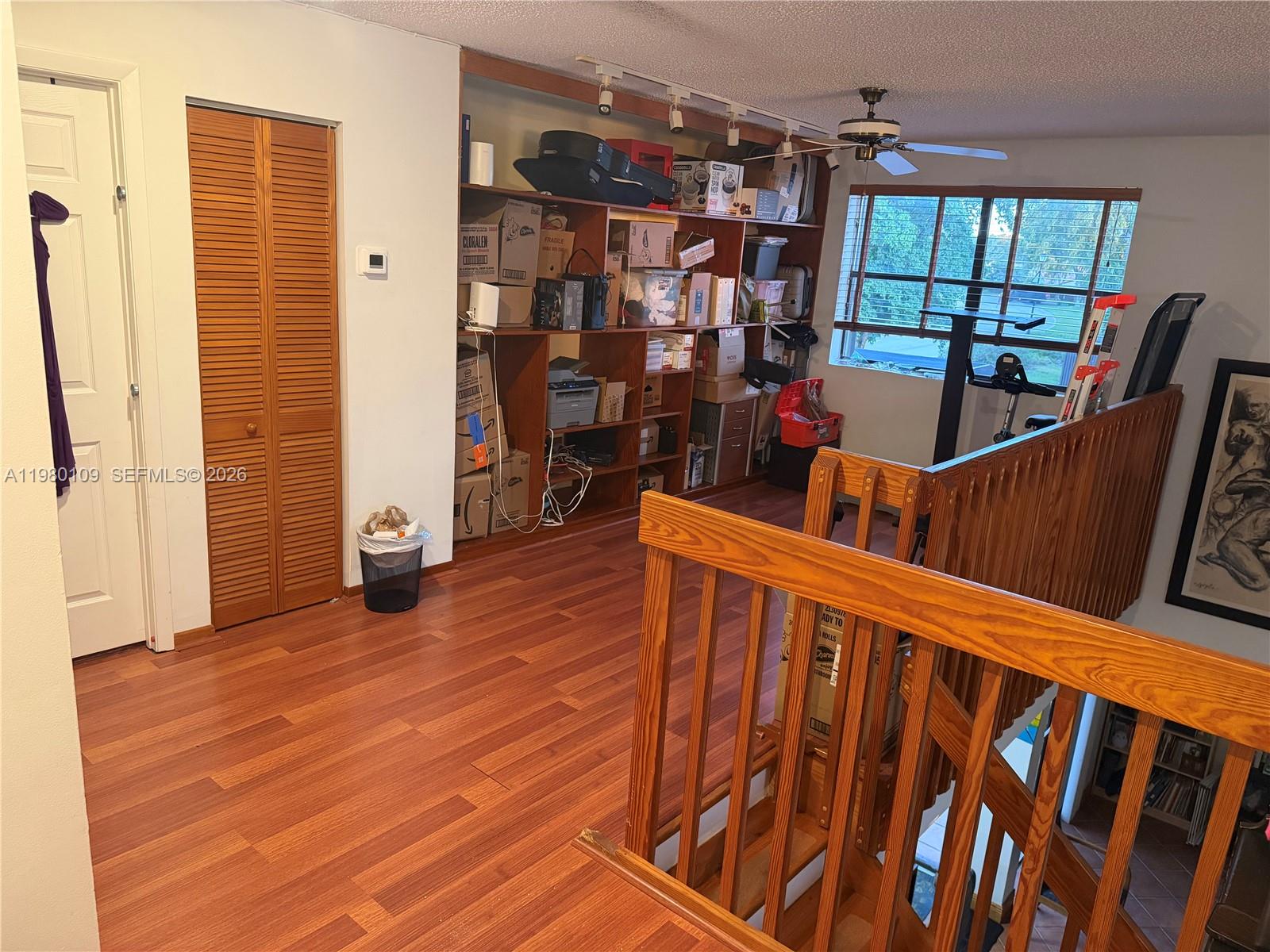 A room with wood-look flooring, built-in shelving, a ceiling fan, and a wooden staircase railing — 15202 SW 46th Ln # 75, Miami FL 33185, MIAMI, FL