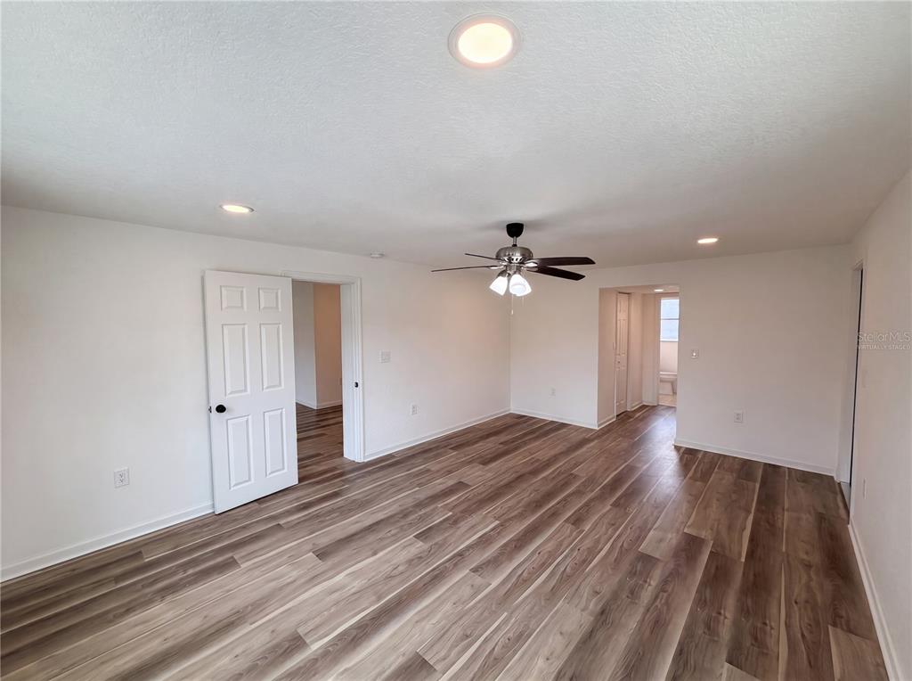An empty room features wood-look flooring, a ceiling fan, and white walls — 567 BAYWOOD DRIVE N, DUNEDIN, FL