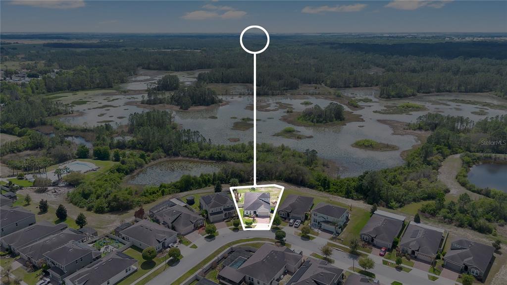 An aerial view shows a single-family house situated at the edge of a large wetland — 116 WHIRLAWAY DRIVE, DAVENPORT, FL