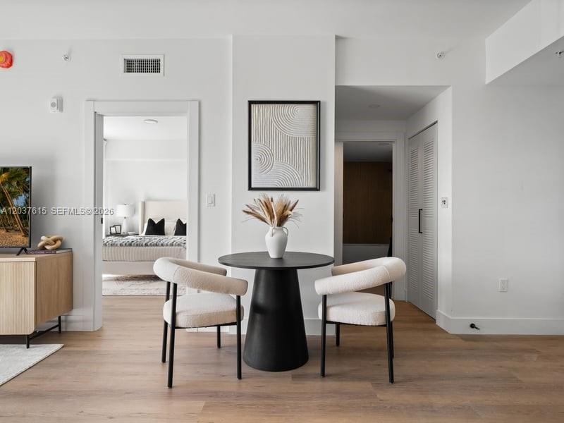 A dining area features a round black table and two white chairs on wood flooring — 2479 NE 192nd St # 207, Miami FL 33180, MIAMI, FL