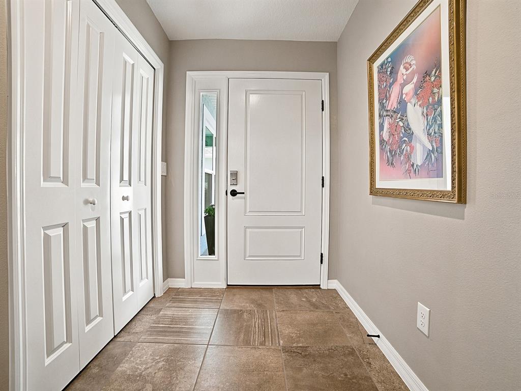 An entryway features tiled flooring, a white front door with a sidelight, and a closet — 3394 RANDI ROAD, THE VILLAGES, FL
