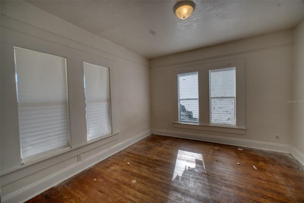 An empty room features white walls, hardwood floors, and two sets of windows — 128 AVENUE D SW, WINTER HAVEN, FL