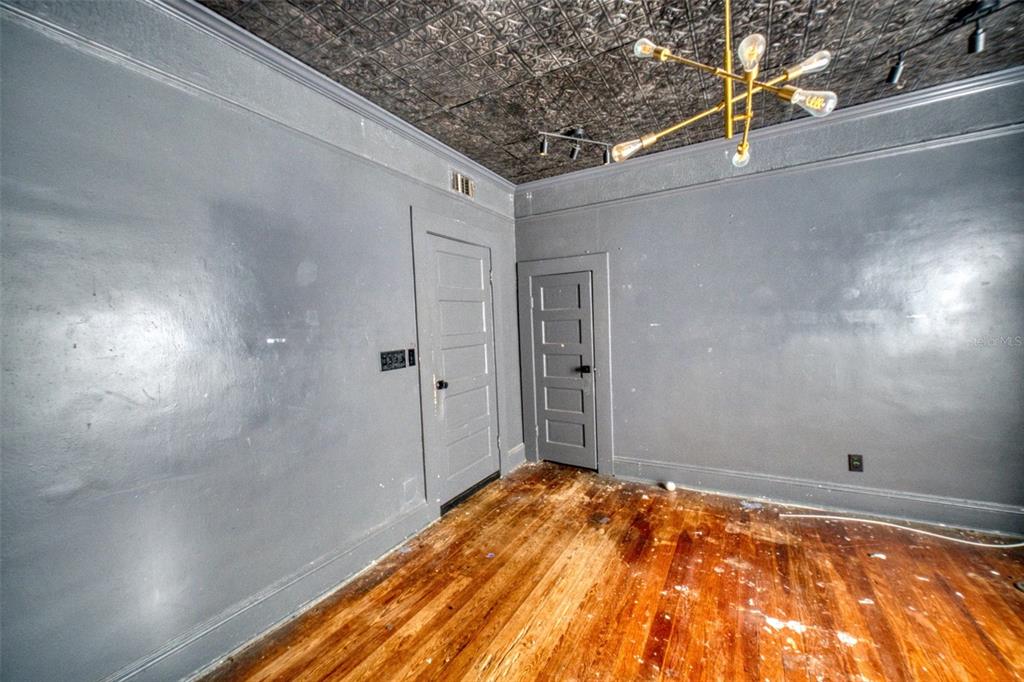 A room with gray walls, a patterned tin ceiling, a gold chandelier, and hardwood floors — 128 AVENUE D SW, WINTER HAVEN, FL
