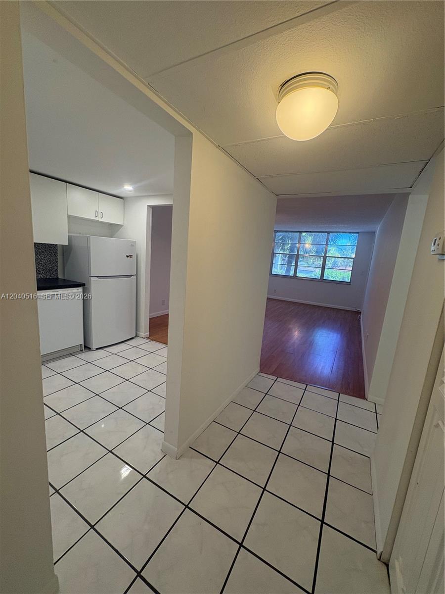 A tiled entryway leads to a kitchen on the left and a wood-floored living area — 2741 Taft St # 211, Hollywood FL 33020, HOLLYWOOD, FL