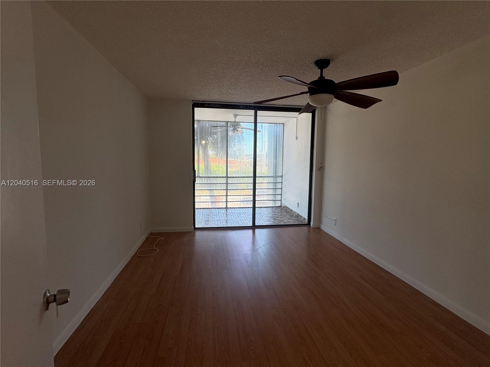 An empty room with wood-look flooring, a ceiling fan, and a sliding glass door to a balcony — 2741 Taft St # 211, Hollywood FL 33020, HOLLYWOOD, FL
