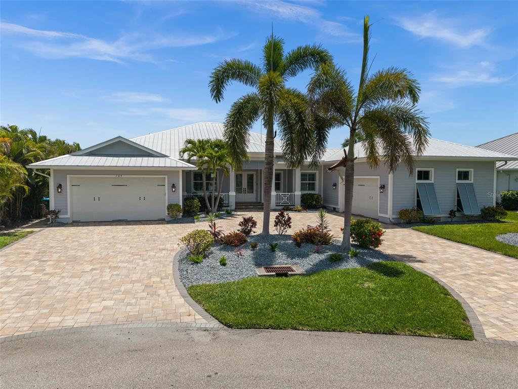 An aerial view shows three waterfront houses with pools and boat docks along a canal — 105 SW 52ND STREET, CAPE CORAL, FL