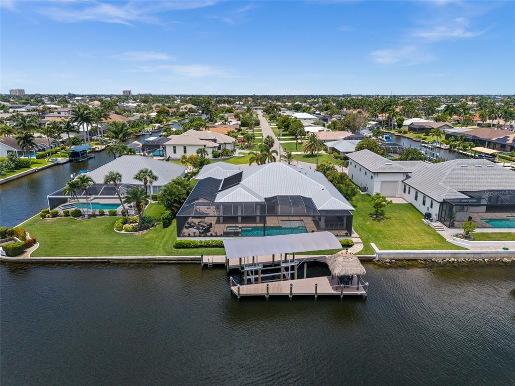 A single-story house with a light gray exterior, metal roof, and a paved circular driveway — 105 SW 52ND STREET, CAPE CORAL, FL