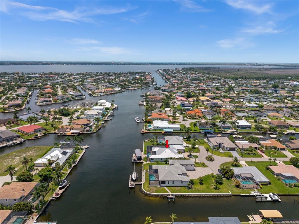 An aerial view shows a waterfront house with a pool, screened lanai, and private dock — 105 SW 52ND STREET, CAPE CORAL, FL