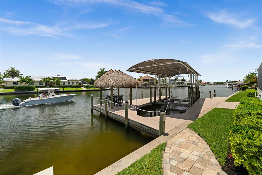 A boat dock with a thatched-roof tiki hut and a covered boat lift on a canal — 105 SW 52ND STREET, CAPE CORAL, FL