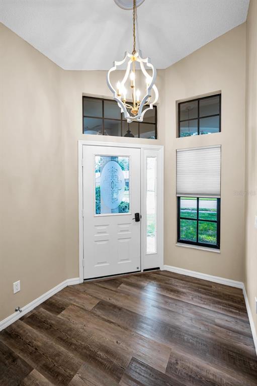 An entryway with wood-look flooring, a white front door, and a decorative hanging chandelier — 9307 PALM HAVEN COURT, NEW PORT RICHEY, FL