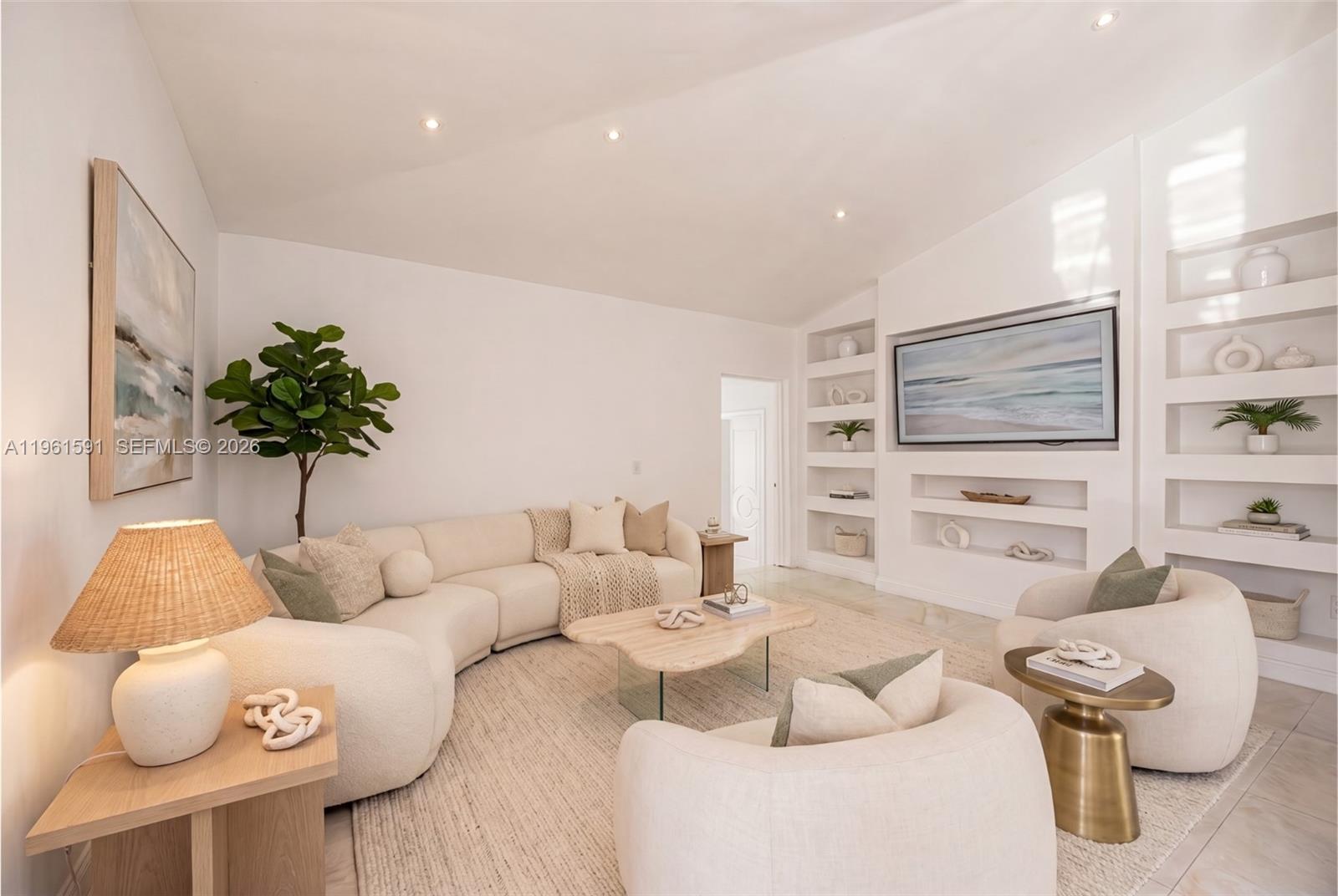 A bright living room features a curved sofa, two armchairs, and built-in wall shelving — 1101 Coral Way, Coral Gables FL 33134, CORAL GABLES, FL