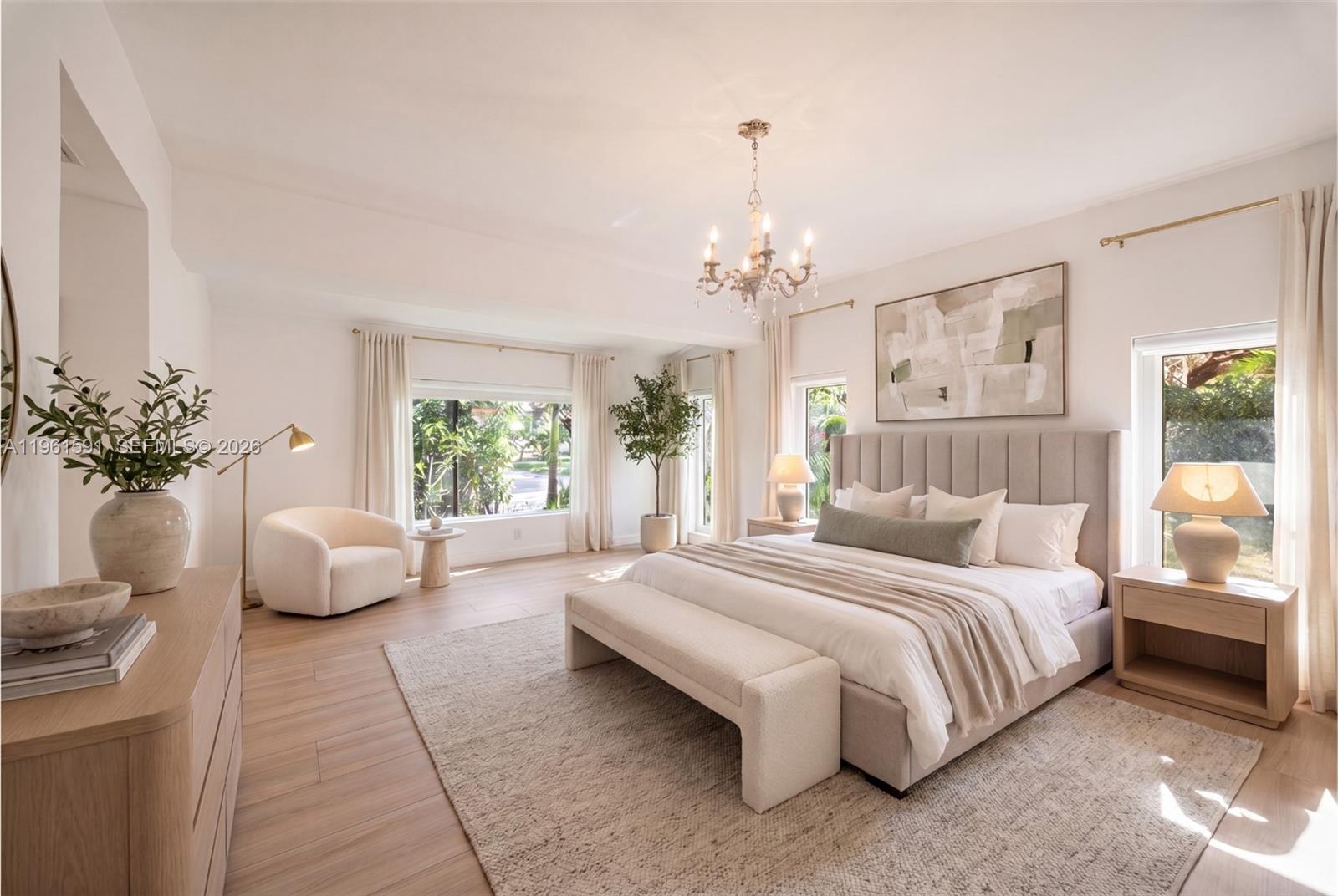 A bright bedroom features a tufted headboard, a chandelier, and light wood flooring — 1101 Coral Way, Coral Gables FL 33134, CORAL GABLES, FL