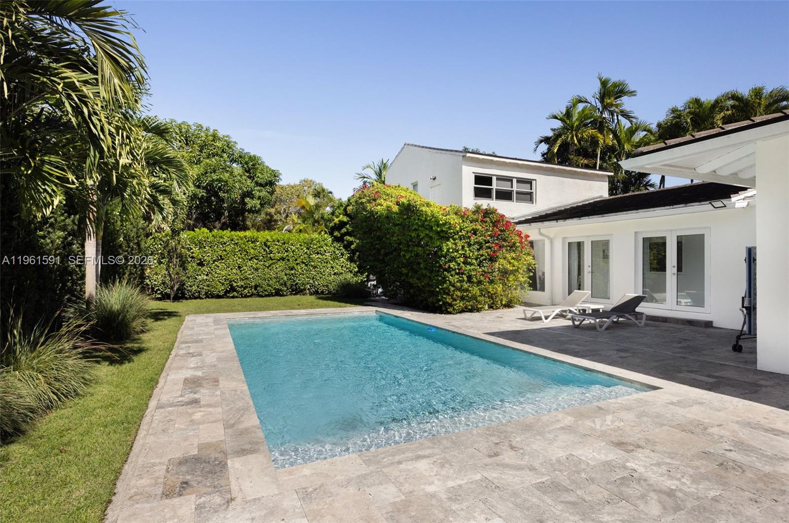 A rectangular swimming pool sits on a stone patio next to a white house — 1101 Coral Way, Coral Gables FL 33134, CORAL GABLES, FL
