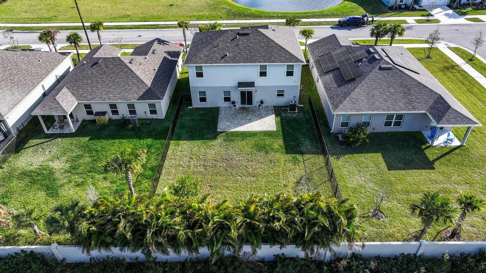 An aerial view shows three suburban houses with fenced backyards and a shared paved patio — 514 Raspberry Road, Fort Pierce FL 34981, FORT PIERCE, FL