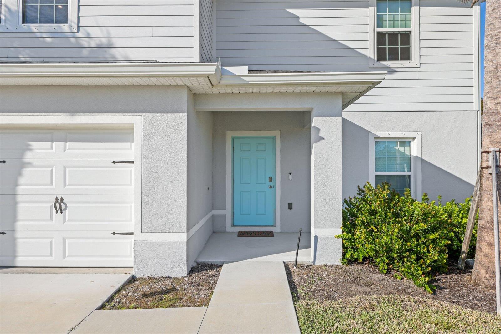 The exterior of a two-story home features a light blue front door and garage — 514 Raspberry Road, Fort Pierce FL 34981, FORT PIERCE, FL