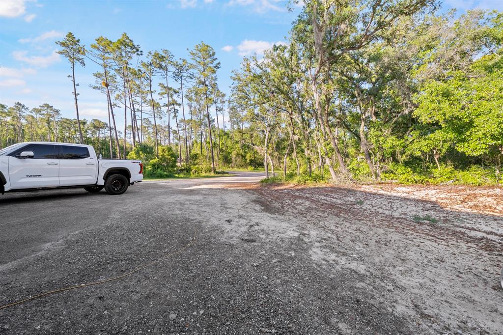 A white pickup truck is parked on a gravel lot next to a wooded area — 1000 SR 415, DELTONA, FL