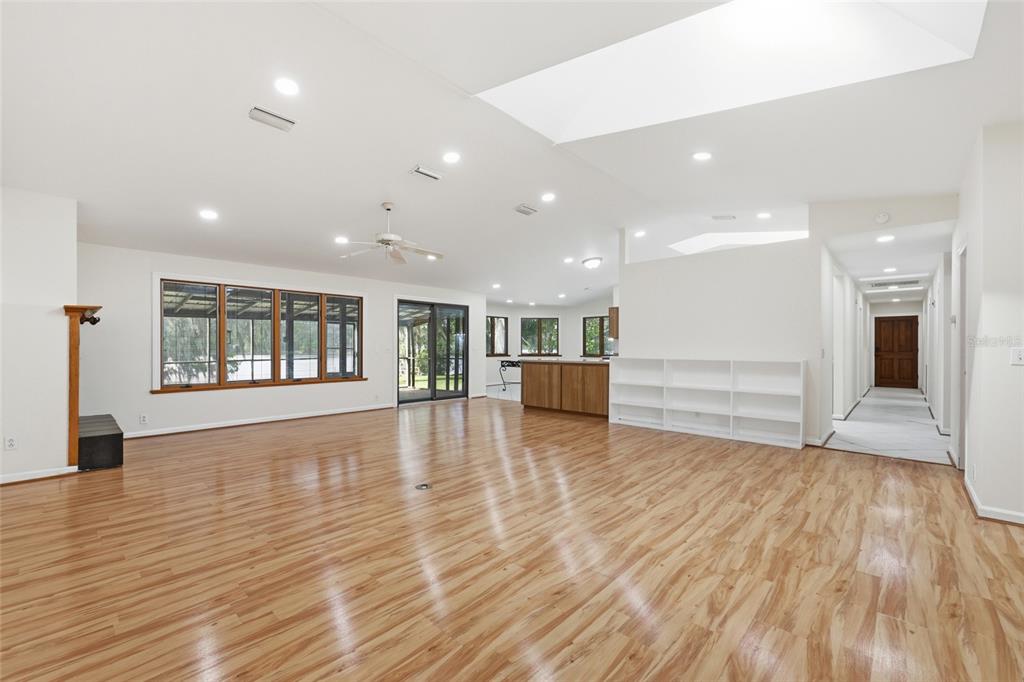 A spacious, open-concept living area with light wood flooring, recessed lighting, and a white bookshelf — 125 TWIN LAKE GROVE DRIVE, INTERLACHEN, FL