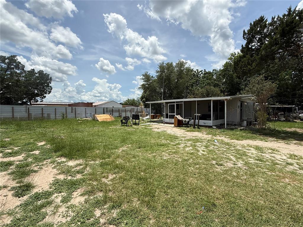 A single-story mobile home with a screened porch sits on a large, grassy, sandy lot — 10360 SE 131ST LANE, OCKLAWAHA, FL